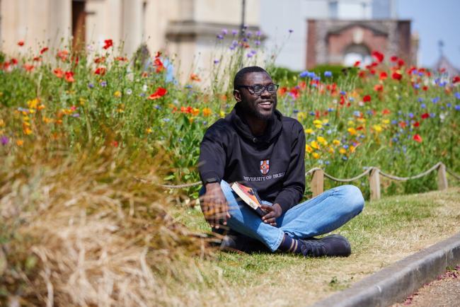 smiling student sitting in wild flowers